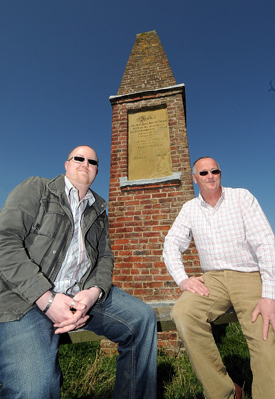 Martin Goff and Derek Gray sitting in front of the Wold Cottage monument